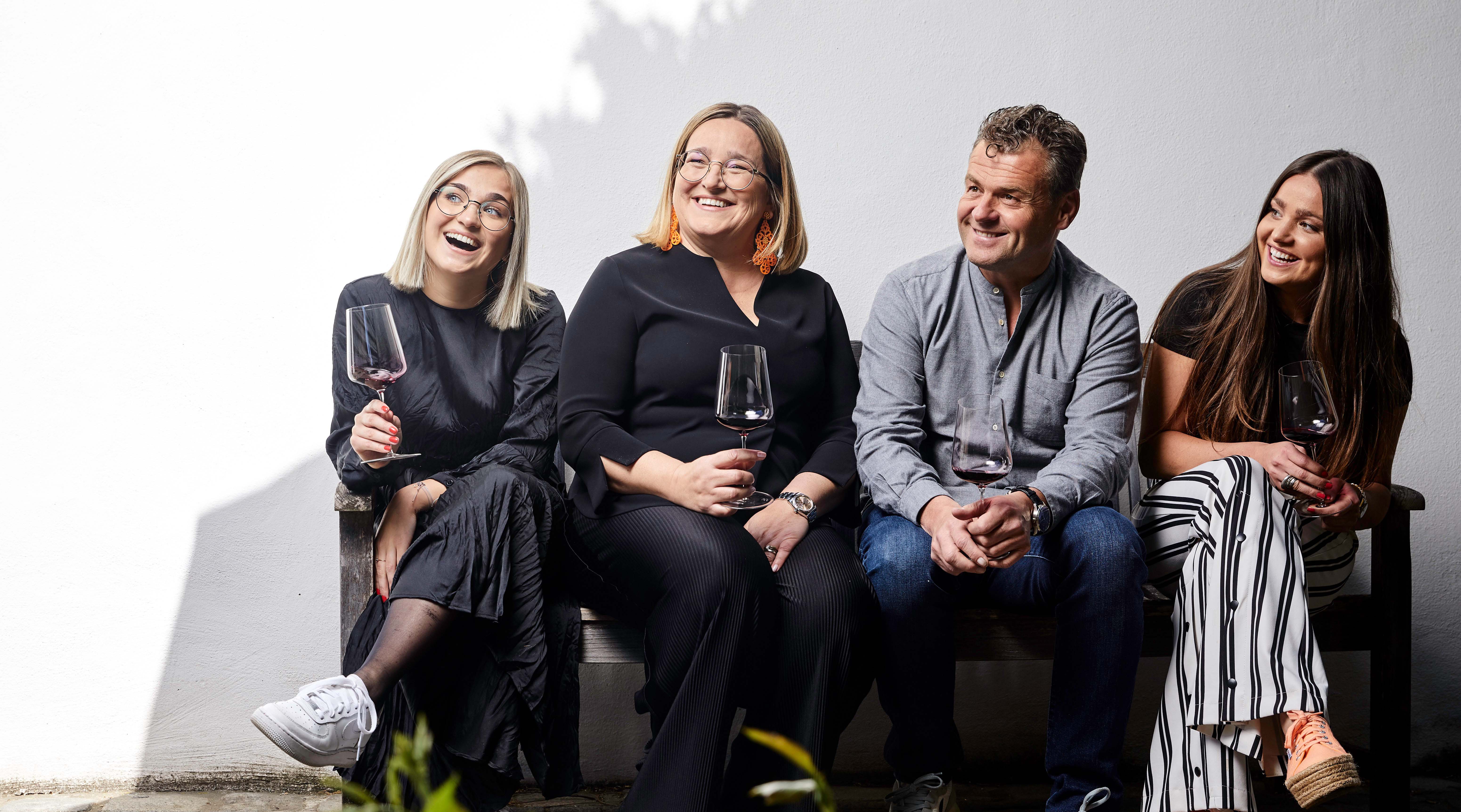 die ganze Familie Markowitsch sitzt auf einer Bank und lacht